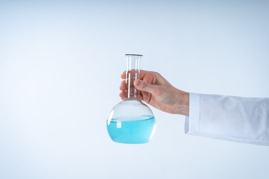 Chemist woman holding medical glass bottle with liquid, making laboratory research