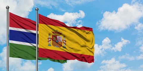 Gambia and Spain flag waving in the wind against white cloudy blue sky together. Diplomacy concept, international relations.
