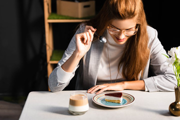 happy redhead woman eating cake with coffee in cafe