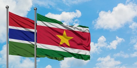 Gambia and Suriname flag waving in the wind against white cloudy blue sky together. Diplomacy concept, international relations.