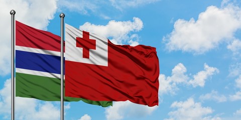Gambia and Tonga flag waving in the wind against white cloudy blue sky together. Diplomacy concept, international relations.