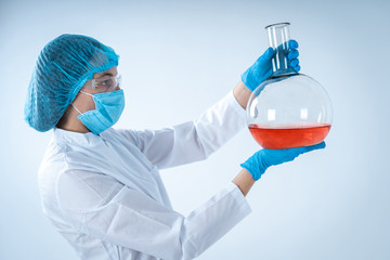 Scientific woman holding medical glass bottle with liquid, making laboratory analysis