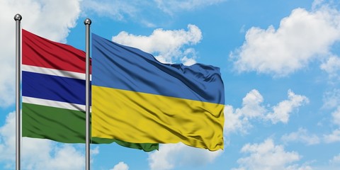 Gambia and Ukraine flag waving in the wind against white cloudy blue sky together. Diplomacy concept, international relations.
