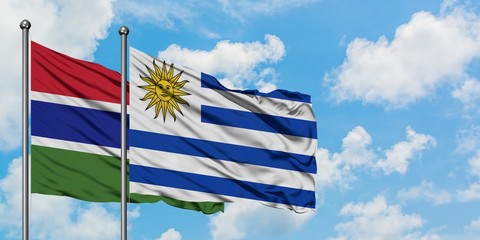 Gambia and Uruguay flag waving in the wind against white cloudy blue sky together. Diplomacy concept, international relations.