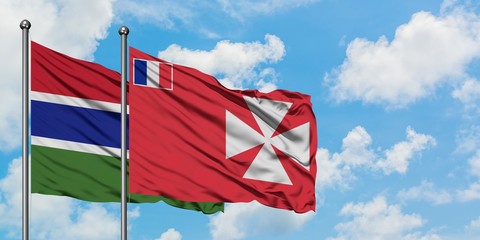Gambia and Wallis And Futuna flag waving in the wind against white cloudy blue sky together. Diplomacy concept, international relations.