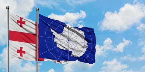 Georgia and Antarctica flag waving in the wind against white cloudy blue sky together. Diplomacy concept, international relations.