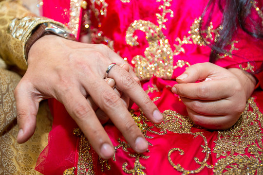 Groom places the wedding ring on the Bride’s finger at Bangladesh. Close up image.