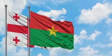 Georgia and Burkina Faso flag waving in the wind against white cloudy blue sky together. Diplomacy...