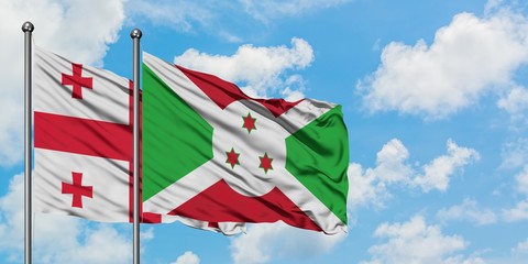 Georgia and Burundi flag waving in the wind against white cloudy blue sky together. Diplomacy...