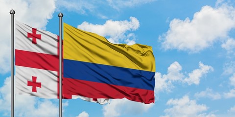 Georgia and Colombia flag waving in the wind against white cloudy blue sky together. Diplomacy concept, international relations.