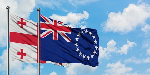 Georgia and Cook Islands flag waving in the wind against white cloudy blue sky together. Diplomacy...