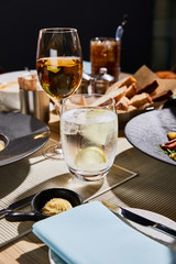 water with ice and lemon near glass of white wine on table in restaurant