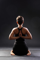 Obraz premium young woman doing yoga exercise on mat in Virasana or Hero Pose with reversed prayer or namaste in studio