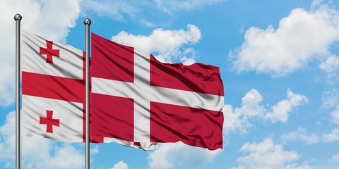 Georgia and Denmark flag waving in the wind against white cloudy blue sky together. Diplomacy concept, international relations.
