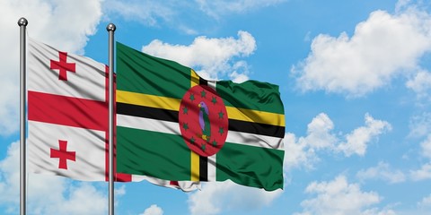 Georgia and Dominica flag waving in the wind against white cloudy blue sky together. Diplomacy...