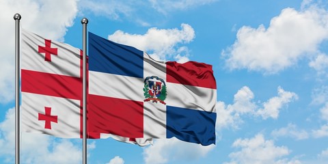 Georgia and Dominican Republic flag waving in the wind against white cloudy blue sky together....