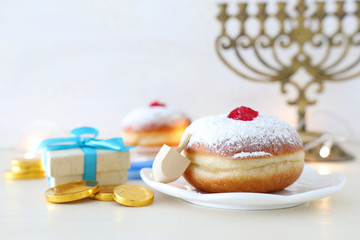 religion image of jewish holiday Hanukkah background with spinning top and doughnut over white background