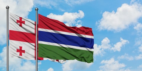 Georgia and Gambia flag waving in the wind against white cloudy blue sky together. Diplomacy...