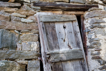Angled wooden door at the entrance of an abandoned house in the Alps