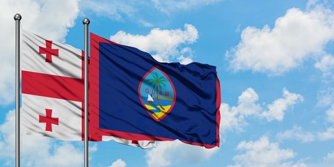 Georgia and Guam flag waving in the wind against white cloudy blue sky together. Diplomacy concept, international relations.