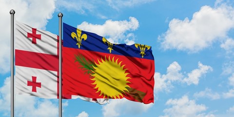 Georgia and Guadeloupe flag waving in the wind against white cloudy blue sky together. Diplomacy concept, international relations.