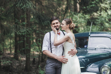 Bride and groom hugging in a forest near car