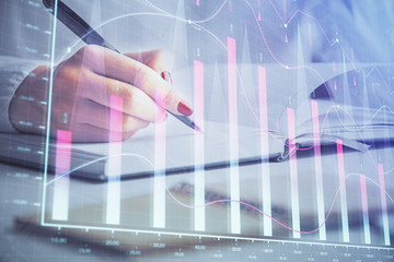 Multi exposure of woman's hands making notes with forex graph hologram. Concept stock market analysis.