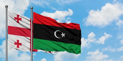 Georgia and Libya flag waving in the wind against white cloudy blue sky together. Diplomacy concept, international relations.