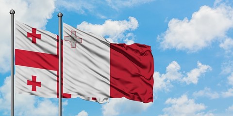 Georgia and Malta flag waving in the wind against white cloudy blue sky together. Diplomacy concept, international relations.