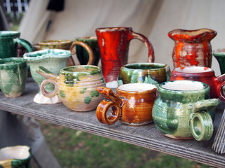 Objects of folk crafts. Ceramic dishes on a wooden bench.