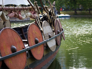 Fototapeta na wymiar A fragment of the historical full-scale reconstruction of the battle rook. The boat is equipped with a sail and oars, shields on the sides protected the soldiers.