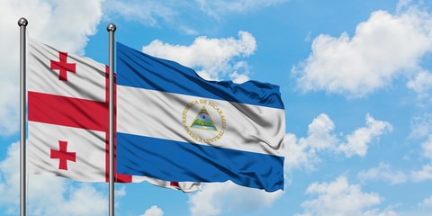 Georgia and Nicaragua flag waving in the wind against white cloudy blue sky together. Diplomacy concept, international relations.