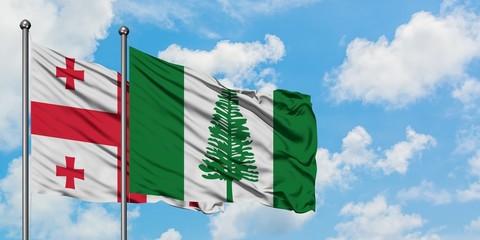 Georgia and Norfolk Island flag waving in the wind against white cloudy blue sky together. Diplomacy concept, international relations.