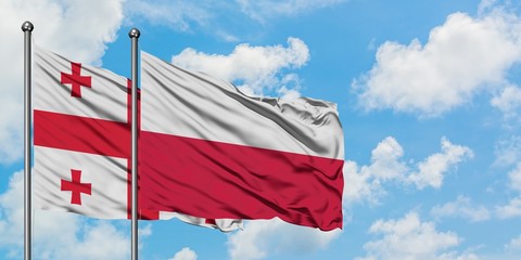 Georgia and Poland flag waving in the wind against white cloudy blue sky together. Diplomacy concept, international relations.