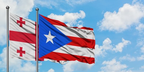 Georgia and Puerto Rico flag waving in the wind against white cloudy blue sky together. Diplomacy concept, international relations.