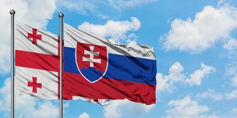 Georgia and Slovakia flag waving in the wind against white cloudy blue sky together. Diplomacy concept, international relations.
