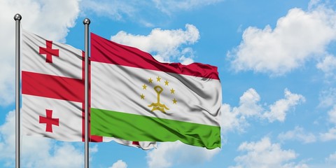 Georgia and Tajikistan flag waving in the wind against white cloudy blue sky together. Diplomacy concept, international relations.