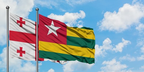 Georgia and Togo flag waving in the wind against white cloudy blue sky together. Diplomacy concept, international relations.