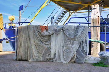 Fishing nets stored over railing of fishing boat anchored at harbor
