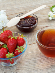 Glass cup of tea, strawberries with white jasmine flowers