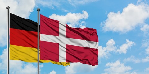 Germany and Denmark flag waving in the wind against white cloudy blue sky together. Diplomacy concept, international relations.