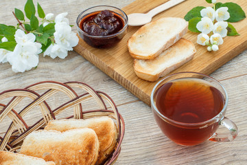 Glass cup of tea, bread, strawberries with white jasmine flowers