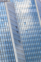 Fototapeta na wymiar Abstract fragment of modern business architecture made of glass and steel with reflection of blue sky and clouds