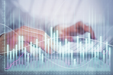 Double exposure of graph with man typing on computer in office on background. Concept of hard work.