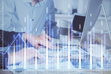 Multi exposure of chart with man typing on computer in office on background. Concept of hard work.