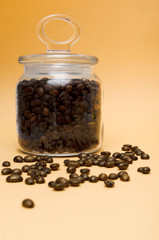 glass jar with roasted mocha coffee beans on a pumpkin background gilded grains