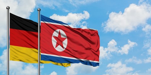 Germany and North Korea flag waving in the wind against white cloudy blue sky together. Diplomacy concept, international relations.