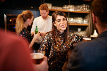 Group of friends drinking beer, chatting and having good time at pub. Night out.
