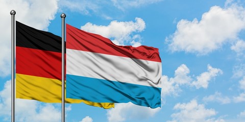 Germany and Luxembourg flag waving in the wind against white cloudy blue sky together. Diplomacy...