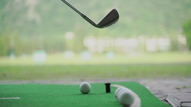 Close up man takes a golf swing at a driving range